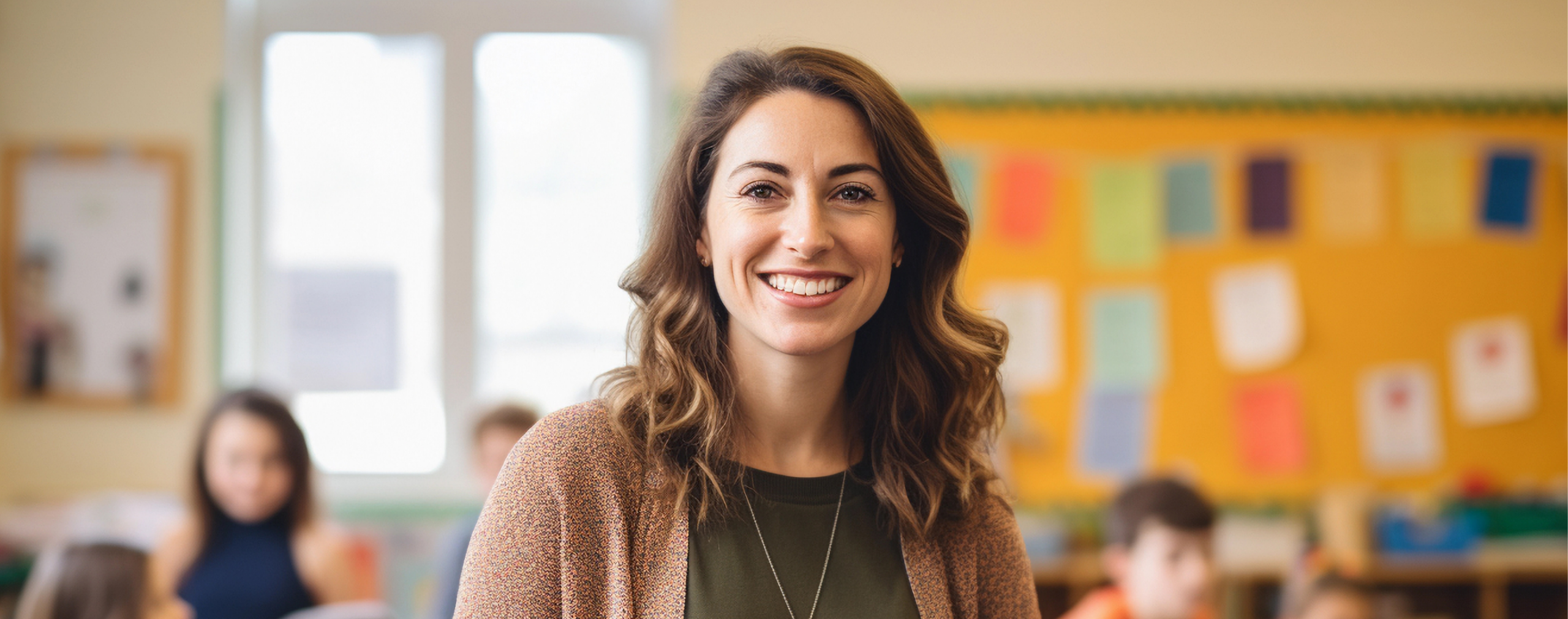 Smiling female educator standing confidently in a bright classroom after completing her alternative teacher certification.